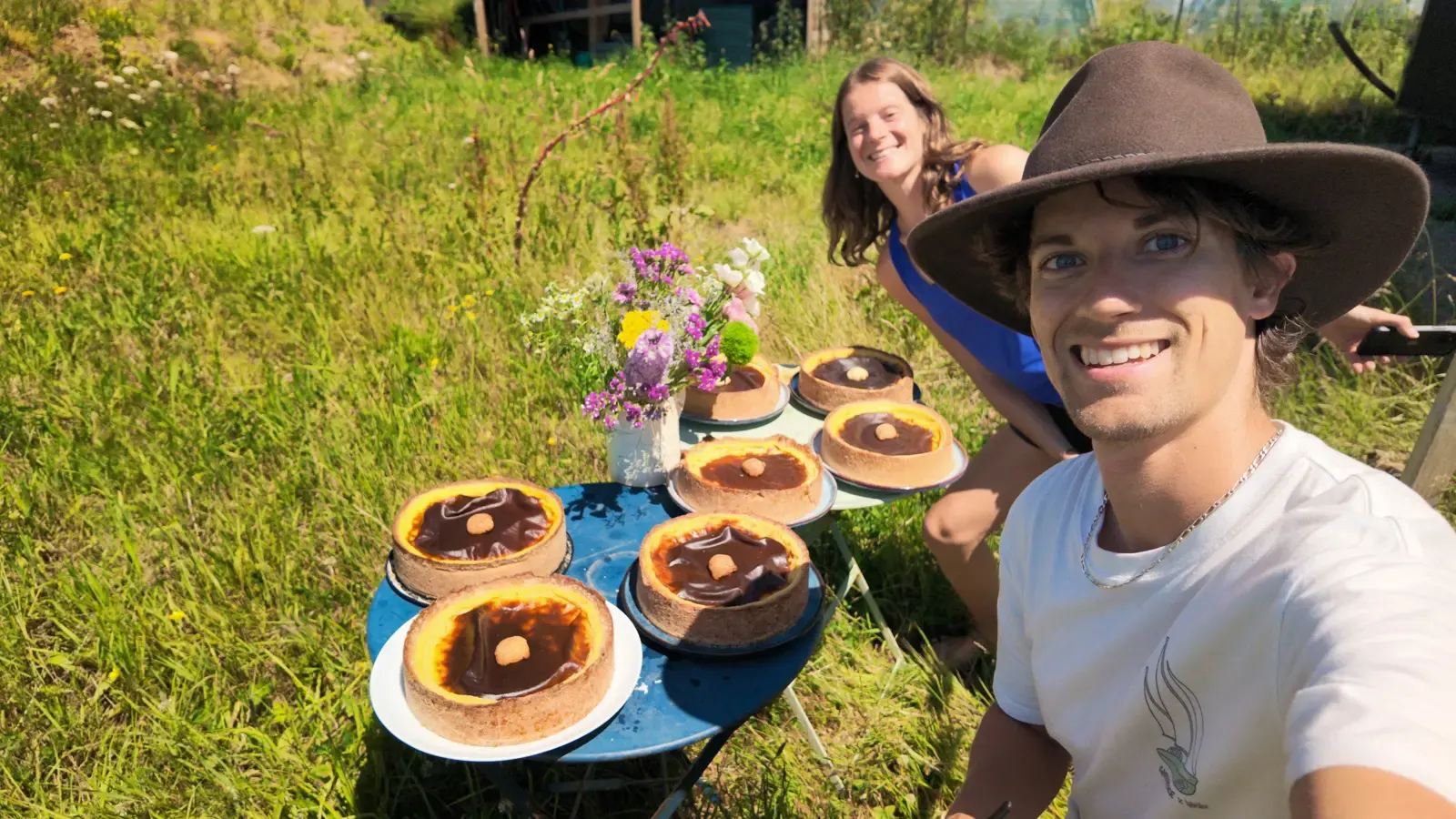 A selfie of Guillaume and Mylene in front of seven freshly baked custard tarts.